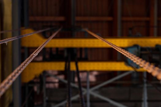 Upward view to long steel chains hanged on steel constructions