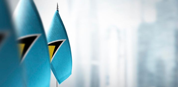 Small flags of Saint Lucia on a blurry background of the city.