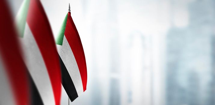 Small flags of Sudan on a blurry background of the city.