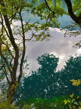 Reflection of clouds and trees in a mountain lake on a cloudy day