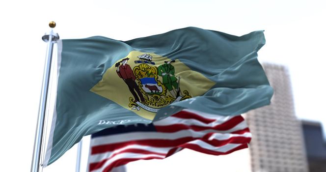 the flag of the US state of Delaware waving in the wind with the American stars and stripes flag blurred in the background. On December 7, 1787, Delaware became the first state of the United States
