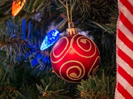 Red bauble with golden ornament on pine tree brench. Closeup look of Christmas decorations