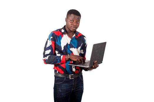 young african man standing on white background with laptop watching the camera.