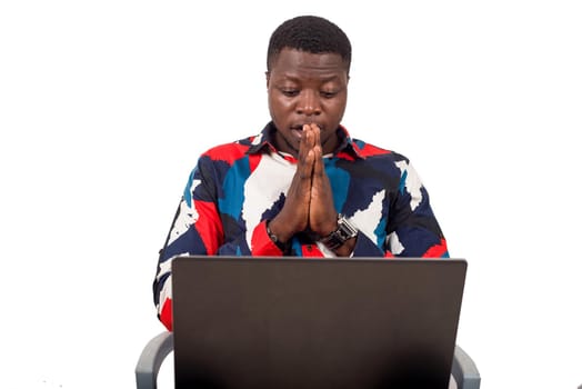 young african sitting in multicolored shirt with computer thinking.