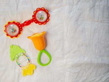 On a crumpled white background there are 3 rattles for newborns. High quality photo