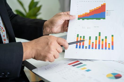 Asian accountant working and analyzing financial reports project accounting with chart graph in modern office, finance and business concept.