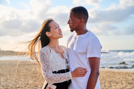 Loving romantic hugging young multiethnic couple on seashore. Happy african man and asian woman together. Love, relationship, dating, happiness, interracial family, tourism, travel, people concept