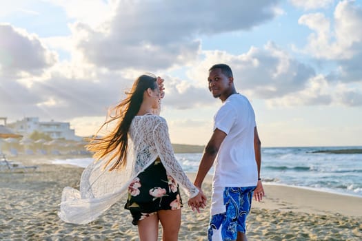 Portrait of beautiful young couple holding hands on beach. Happy loving african man and asian woman walking together. People love relationship multiethnic family, vacation, tourism concept