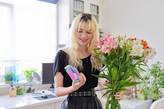 Birthday party, female teenager with bouquet of flowers and surprise gift box in her hands, at home in room. Teens, 17, 18 years old, holiday, happiness joy concept