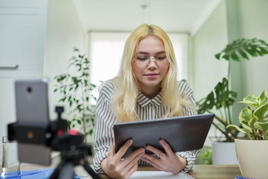 Online lesson, distance learning, e-learning. Female teenager student talking looking at smartphone webcam using digital tablet. High school, technology in education