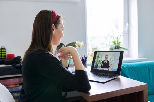 Woman teacher teaching student teenager online using video call on laptop, female sitting at table at home, studying working remotely, e-education, individual lesson