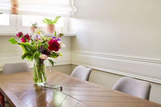 Bouquet of bright flowers on the table in jug. Flowers and buds of peonies irises lupine, season spring summer, home natural decor, holiday, gift concept, copy space