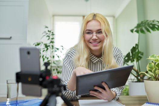 Online lesson, distance learning, e-learning. Female teenager student talking looking at smartphone webcam using digital tablet. High school, technology in education