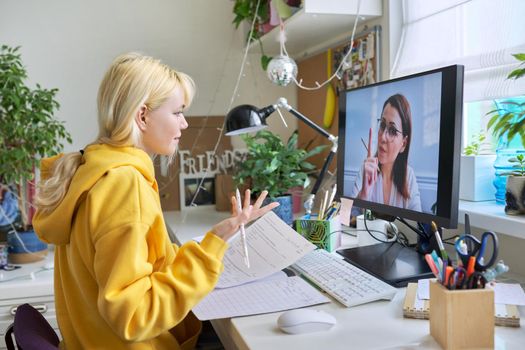 Online learning, e-education, virtual lesson. Girl teenager studies sitting at home using computer, talking online with female teacher, video consultation conference. Modern technologies in education