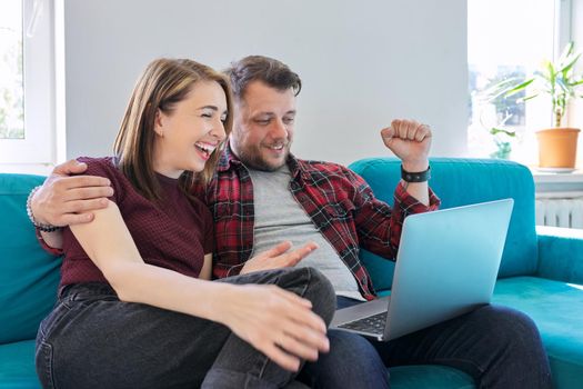 Luck, happiness, joy, victory, won, happy emotional middle aged couple looking in laptop monitor sitting at home on sofa in living room