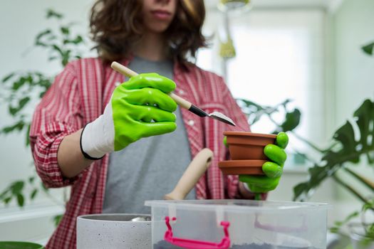 Teenage guy transplanting houseplants, preparing the soil with perlite vermiculite. Hobbies, leisure, green trends, ecology gardening at home, garden inside