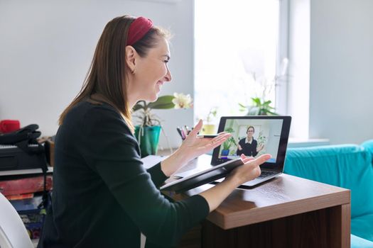 Woman teacher teaching student teenager online using video call on laptop, female sitting at table at home, studying working remotely, e-education, individual lesson