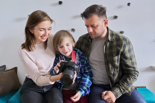 Happy family at home, little son with photo camera with mom and dad. Family, lifestyle, relationships, leisure, home life concept