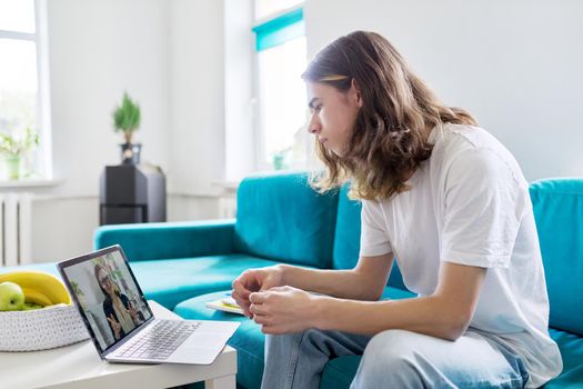 Individual online lesson, teenage boy sitting at home with laptop, studying using remote video consultation, female teacher mentor on computer screen. E-education, technology in teaching, adolescence