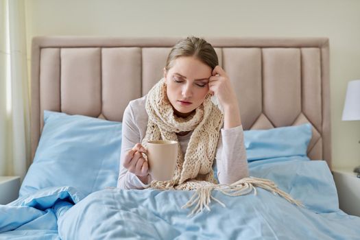 Sick young woman in bed with handkerchief and cup. Flu season, seasonal viral diseases, health, medicine, get sick at home, bed rest, people concept