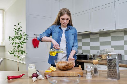 Young woman cooking chicken for the holiday, marinating with spices with black pepper, salt, olive oil and lemon, at home in the kitchen. Culinary blog, recipe, hobby and leisure.