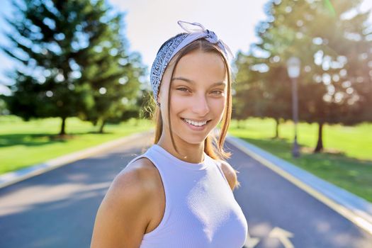 Portrait of beautiful smiling young female outdoors. Hipster teenager on sunny summer day, on the road in the park. Teens, people, age, youth concept