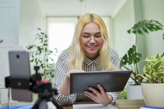 Online lesson, distance learning, e-learning. Female teenager student talking looking at smartphone webcam using digital tablet. High school, technology in education