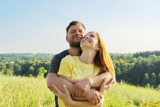 Portrait of happy adult couple on summer sunny day. Beautiful people man and woman embracing in nature, family, happiness, holidays, joy concept