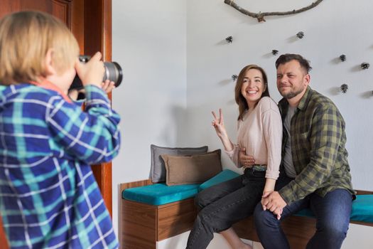 Happy family at home, little son with camera taking photo of hugging parents. Family, lifestyle, relationships, leisure, home life concept