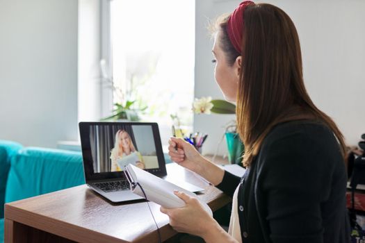 Woman teacher teaching at home online, distance learning. Female sitting at home at table with laptop on virtual meeting with teenage student, video call. E-learning modern technologies in education