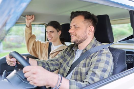 Portrait of father and teenage son together, man driving car, parent and teenage friendship, family middle aged father and teenager son