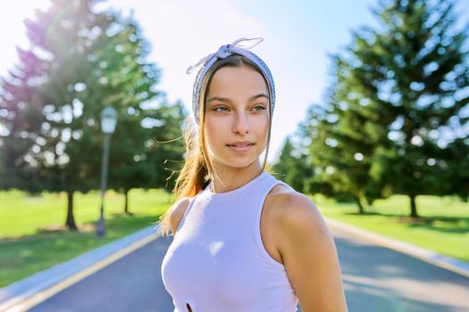 Portrait of beautiful smiling young female outdoors. Hipster teenager on sunny summer day, on the road in the park. Teens, people, age, youth concept