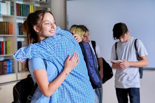 Back to school, to college. Group of teenagers guys and girls are welcome, meeting, smiling, rejoicing. Library classroom schoolroom interior. Adolescence, lifestyle, communication, friendship concept