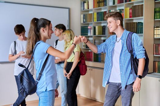 Back to school, to college. Group of teenagers guys and girls are welcome, meeting, smiling, rejoicing. Library classroom schoolroom interior. Adolescence, lifestyle, communication, friendship concept