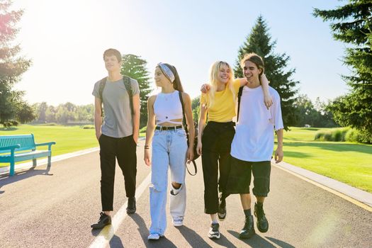 Outdoor, four teenagers walking together on road. Group of happy teenage friends on sunny summer day. Adolescence, youth, friendship, young people, high school college concept