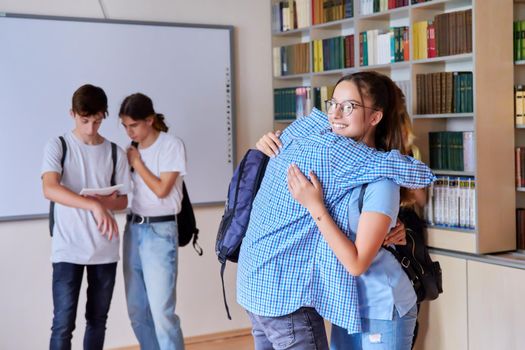 Back to school, to college. Group of teenagers guys and girls are welcome, meeting, smiling, rejoicing. Library classroom schoolroom interior. Adolescence, lifestyle, communication, friendship concept