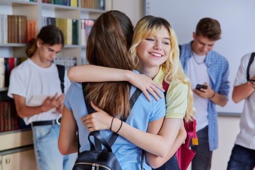 Back to school, to college. Two school girlfriends teenagers are welcome, meeting, smiling, rejoicing. Library classroom schoolroom interior. Adolescence, lifestyle, communication, friendship concept