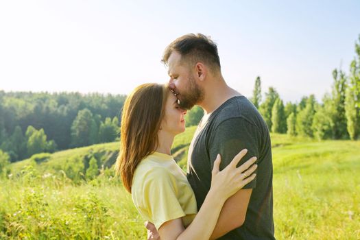 Happy adult couple in love. Man and woman in profile, romantic kiss, nature sky meadow summer background