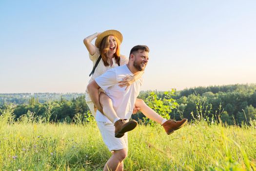Happy laughing adult couple having fun outdoors, nature sky background. People 30s 40s age, relationships, dating, family, happiness, love, lifestyle concept