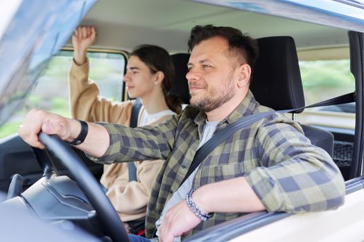 Portrait of father and teenage son together, man driving car, parent and teenage friendship, family middle aged father and teenager son