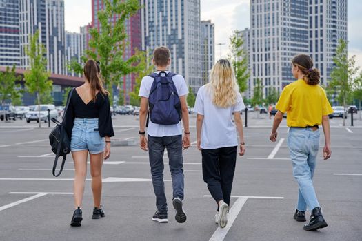 Group of teenagers walking together, back view, urban style, modern city background. Trending youth, lifestyle, friendship, high school, college, adolescence concept