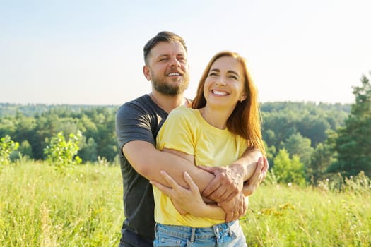 Portrait of happy adult couple on summer sunny day. Beautiful people man and woman embracing in nature, family, happiness, holidays, joy concept