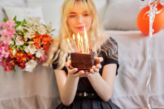 Birthday of female teenager, girl with birthday small cake with burning candles, room, bouquet of flowers, colored balloons background. Holiday, teens, age, celebration concept