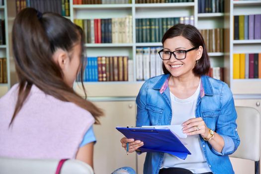 Woman school psychologist, teacher, social worker, mentor working with a teenage girl in the library, office with books. Social assistance, mental health, adolescence, therapy, psychology concept