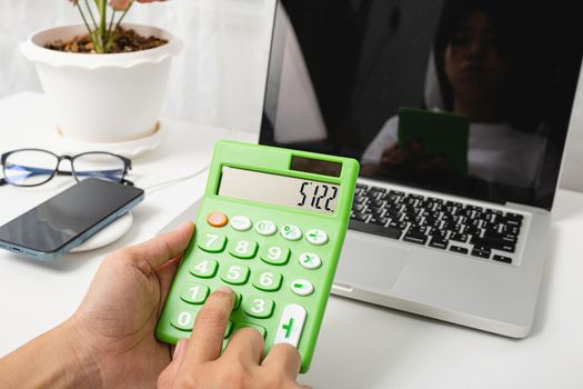 Accountant working and analyzing financial calculating with calculator and laptop computer income-expenditure at office desktop, Business financial and tax systems concept