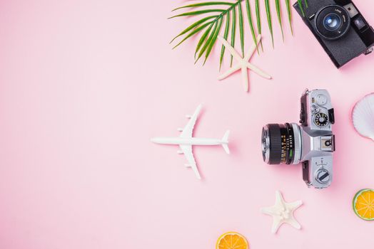 Top view flat lay mockup of retro camera films, airplane, starfish, hat and traveler tropical accessories isolated on pink background with copy space, Business trip, and vacation summer travel concept
