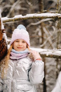 a little girl in a silver jacket in winter goes outside in winter.