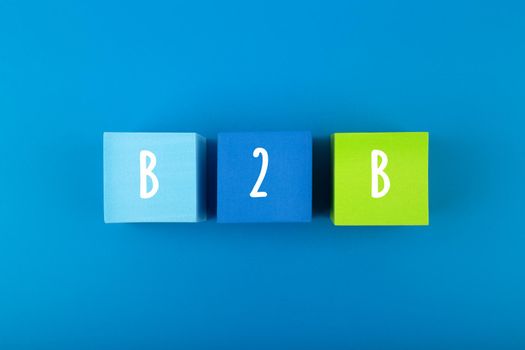 B2B minimal commercial marketing business concept. B2B letters written on multicolored cubes in a row against dark blue background