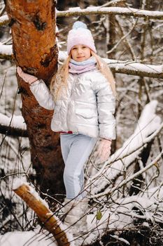 a little girl in a silver jacket in winter goes outside in winter.