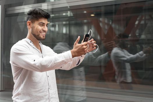 Young man smiling happy doing video call using smartphone at city. High quality photo